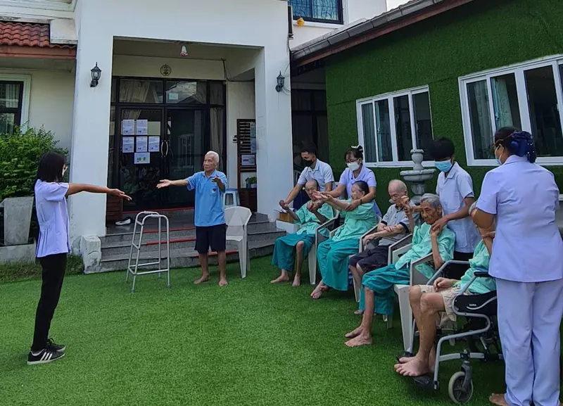 พยาบาลและผู้สูงอายุนั่งหน้าอาคารสาขาปิ่นเกล้า ตลิ่งชัน